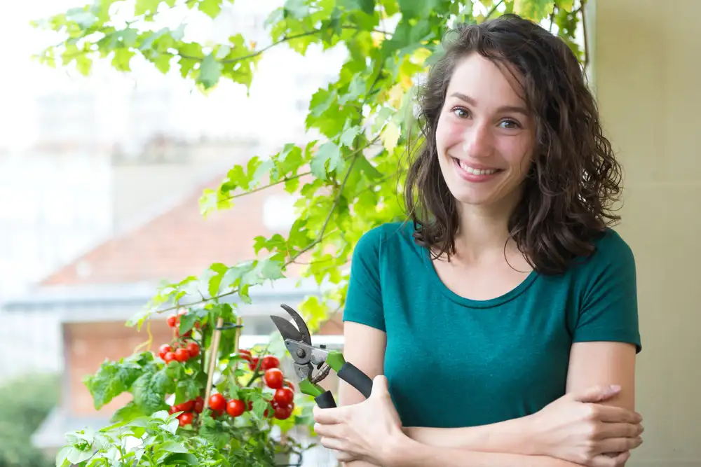 Gemüse auf dem Balkon anbauen: Frau mit Tomaten auf Stadtbalkon